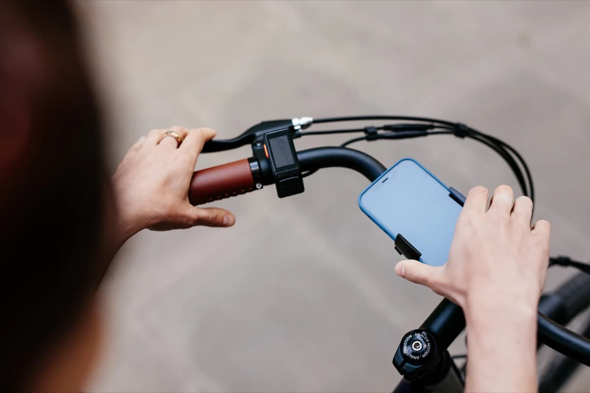 Manos de ciclista en el manubrio con celular montado, listo para usar
